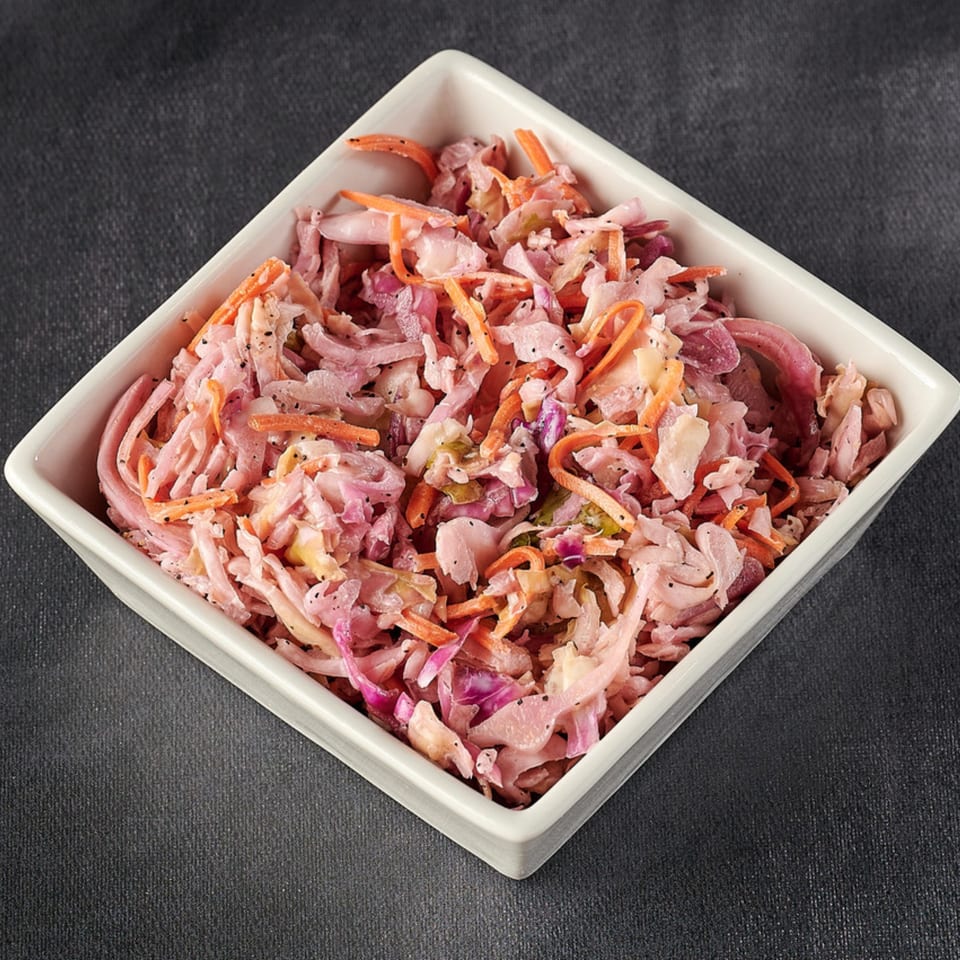 A white square bowl filled with Hot Chicks House of Chicken coleslaw, featuring shredded cabbage and carrots.