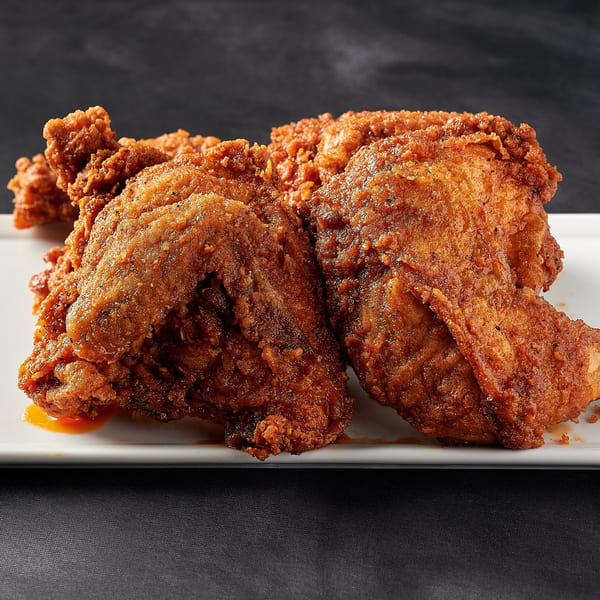 Crispy, golden-brown fried chicken pieces from Hot Chicks House of Chicken, with a hint of sauce.