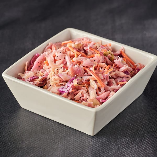 A white square bowl filled with Hot Chicks House of Chicken coleslaw, featuring shredded cabbage and carrots.