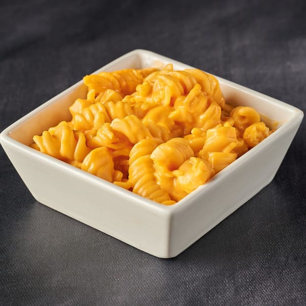 A white square bowl filled with creamy orange macaroni and cheese, a side dish from Hot Chicks House of Chicken.
